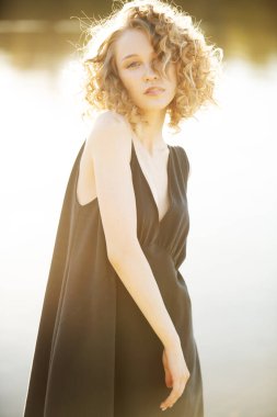 Dışarıda siyah elbiseli güzel bir genç kız poz veriyor. Moda konsepti.