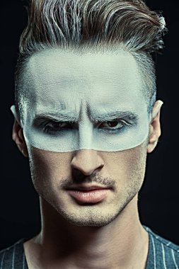 Siyah arka planda beyaz boyalı yakışıklı bir adamın yakın plan sanat portresi. Erkek güzeli, moda. Saç stili ve kozmetik.