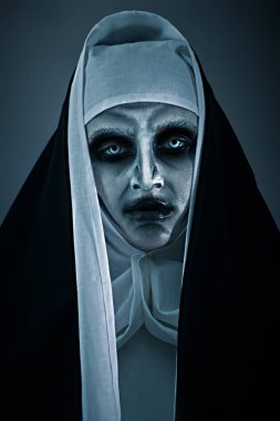 Cadılar Bayramı. Karanlık arka planda kameraya bakan kanlı gözlü korkunç bir rahibenin portresi. Dehşet.