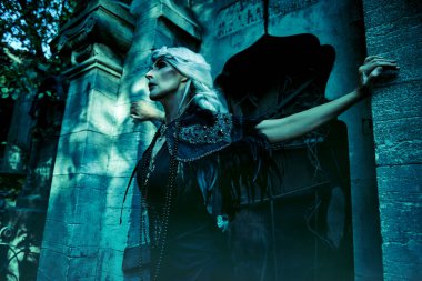 Güzel gri saçlı ve zengin siyah elbiseli aristokrat bir dul kadın mezarlıktaki bir mahzende üzgün duruyor. Kara Dul. Gizemciliğin atmosferi. Cadılar Bayramı.