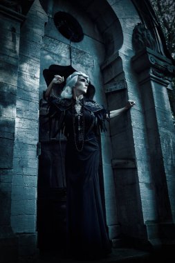 Güzel gri saçlı ve zengin siyah elbiseli aristokrat bir dul kadın mezarlıktaki bir mahzende üzgün duruyor. Kara Dul. Gizemciliğin atmosferi. Cadılar Bayramı.