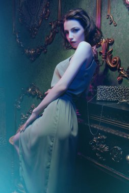 Güzel esmer, gece makyajı ve lüks bir dairede şık bir elbise içinde poz veren güzel bir kız. Moda fotoğrafı.. 