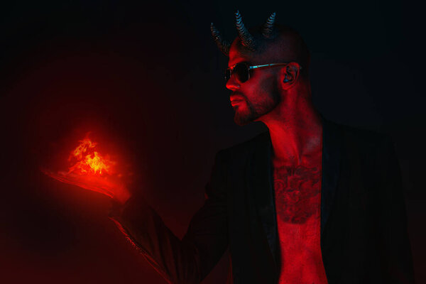 Портрет плохого демона в солнечных очках с огнем в руке. Фильм ужасов, кошмар. Хэллоуин.