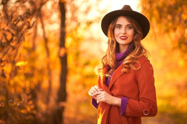 Şapkalı güzel genç bayan sonbahar parkında poz veriyor. Sonbahar güzelliği, moda.
