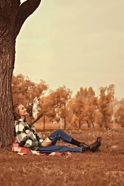 Happy beautiful girl having a rest in an autumn park. Autumn fashion. Happiness.