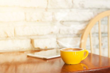 Tablet bilgisayarlı kahve fincanı ahşap masada..