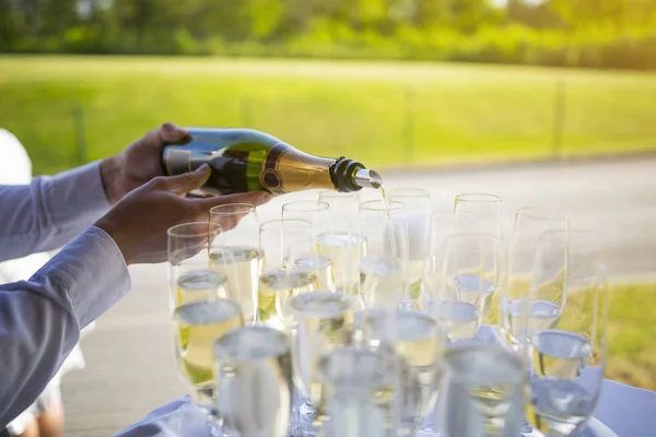 Camarero llenando copas de champán o vino espumoso en un evento —  Fotos de Stock