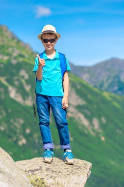 mutlu küçük traveler Dağları arka plan üzerinde bir sırt çantası ile dikey portresi