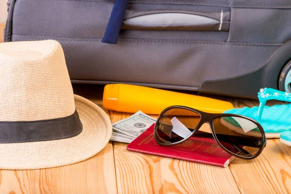 aksesuar ve gerekli belgeler için bir ahşap zemin yakın çekim gri bavula arka plan üzerinde seyahat