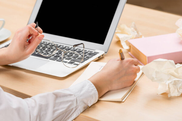 крупным планом женские руки записывают информацию в блокнот и хранят очки
