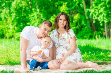 bir yaz parkta çekim bir bebek beklentisiyle genç mutlu bir aile portresi