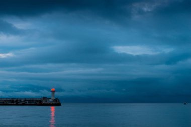 Deniz kıyısı alacakaranlıkta, yağmurlu bulutlar deniz üzerinde güzel deniz feneri