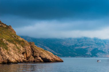 Doğa deniz manzarası - kayalık sahil, sakin deniz ve dramatik gökyüzü