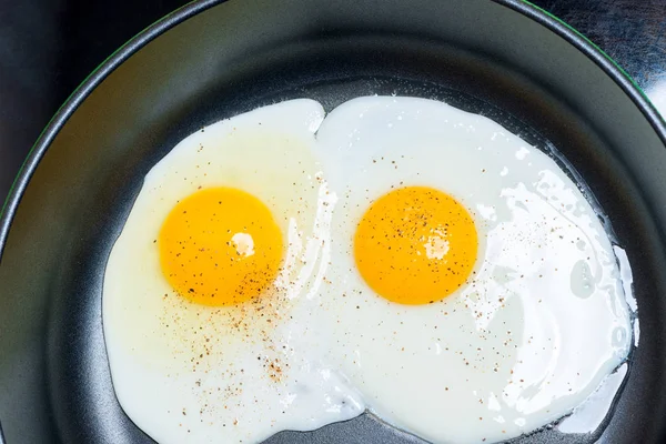 煎蛋从两个鸡蛋在煎锅上煎的顶视图特写镜头 — 图库照片