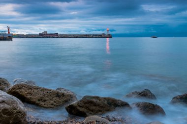 deniz kıyısı denize alacakaranlıkta, yağmurlu bulutlar, deniz feneri görünümü