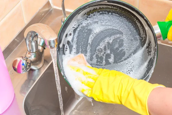 キッチン内での泡をスポンジ鍋を洗う手袋の女性の手のクローズ アップ — ストック写真