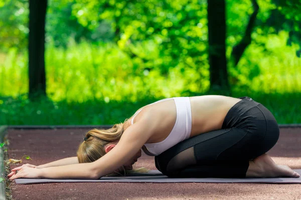 Yoga op een mat in het park, portret van een actieve slanke trainer — Stockfoto