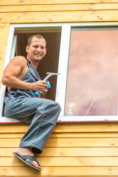 Man professional in overall reinigt het raam in het huis — Stockfoto