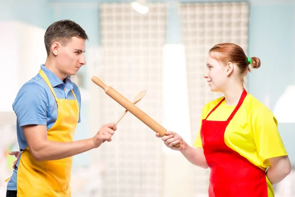 Férfi és nő egy kötény, konyhai eszközök, harc a — Stock Fotó