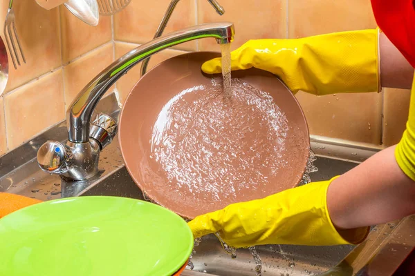 Крупный план рук с тарелками в перчатках - домашняя стирка посуды — стоковое фото