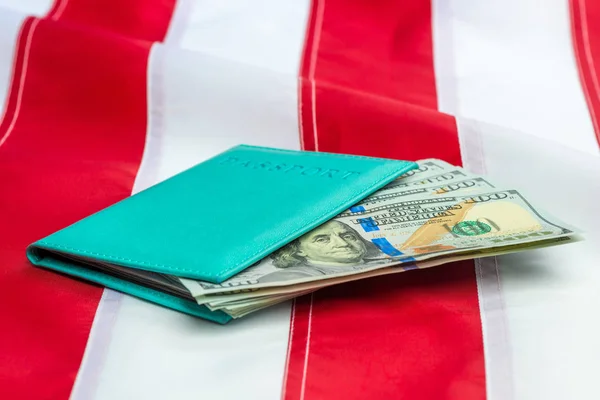 Passaporte recheado com dólares americanos num close-up da bandeira dos EUA — Fotografia de Stock