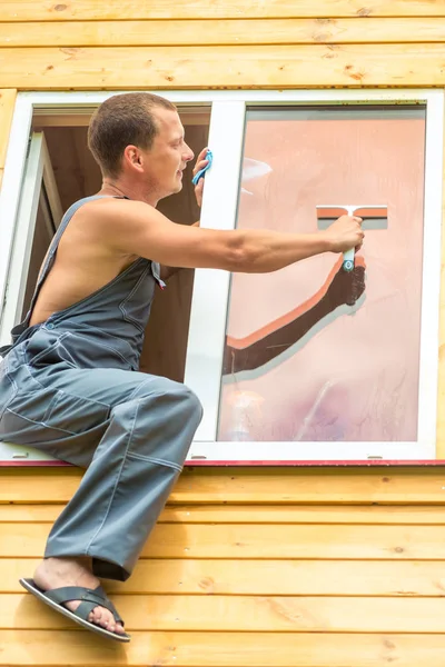 Man professional in overall reinigt het raam in het huis — Stockfoto