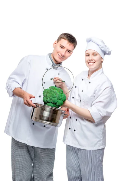 Vertikální portrét kolegů kuchařů s pan a brokolice na bílém — Stock fotografie