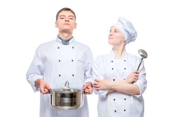 Retrato de un hombre y una mujer en trajes de cocina posando con una sartén en — Foto de Stock