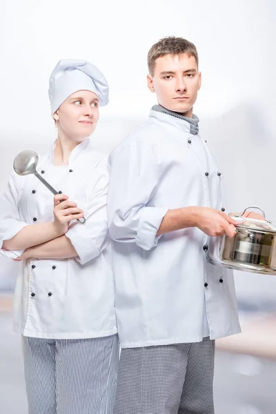 Cocina en trajes con una cacerola y un cucharón posando contra la ba — Foto de Stock