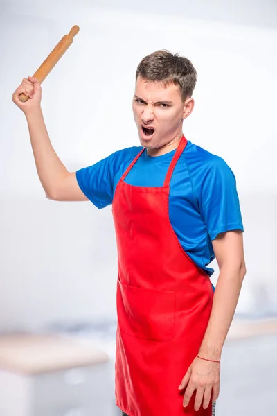 Angry man in an apron with a rolling pin, a portrait on the back — Stock Photo, Image