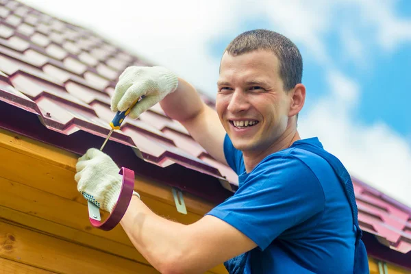 Happy man repareert het dak van het huis, een portret op de — Stockfoto