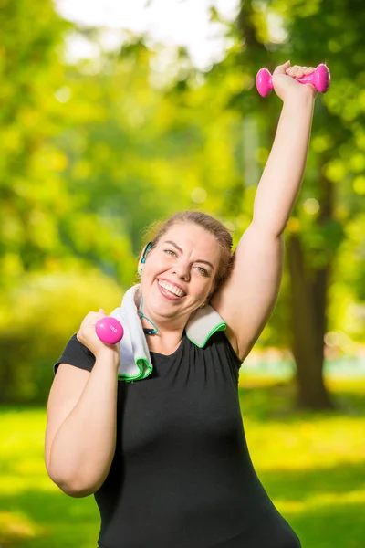 Portrait of happy plus size model with dumbbells during workout — Stock Photo, Image