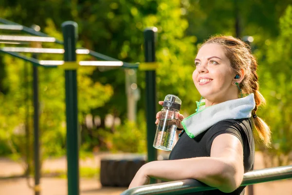 Porträt einer großen Frau mit einer Flasche Wasser neben dem Simulator — Stockfoto