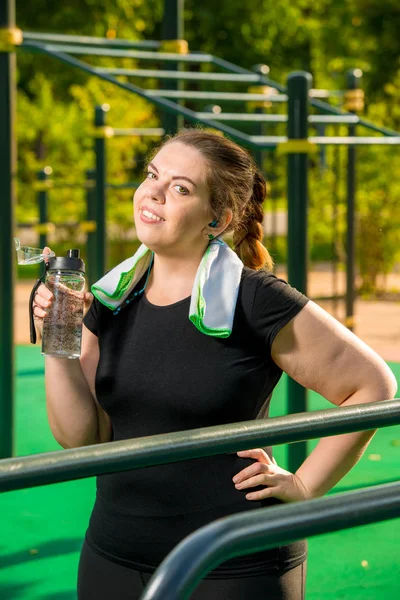 Толстая женщина с бутылкой чистой воды отдыхает после тренировок — стоковое фото