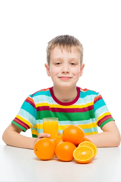 Menino com laranjas e um copo de suco de laranja fresco na mesa — Fotografia de Stock