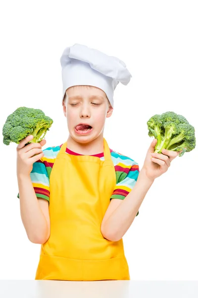 Vertical portrait of a boy who does not like broccoli in a cook' — Stockfoto