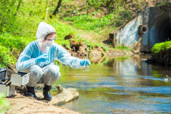 Cientista ambiental com um balão leva uma amostra de água em — Fotografia de Stock