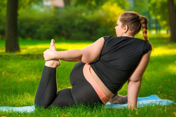 胖女人在公园里做瑜伽，加上大小的女人是非常灵活的 — 图库照片