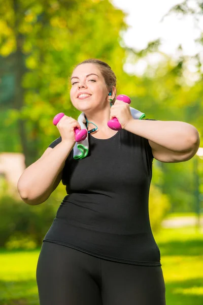 Happy plus size model listens to music with headphones and pract — Stock Photo, Image