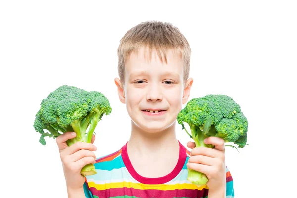 Retrato de um menino com brócolis nas mãos sobre fundo branco em — Fotografia de Stock