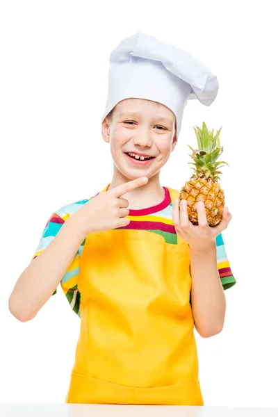 Pequeno cozinheiro em um boné com um mini abacaxi em um fundo branco — Fotografia de Stock