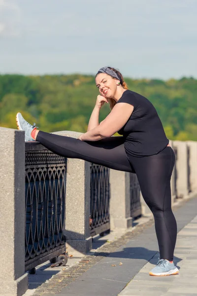 Überdimensionale junge Frau macht Dehnübungen am Damm — Stockfoto