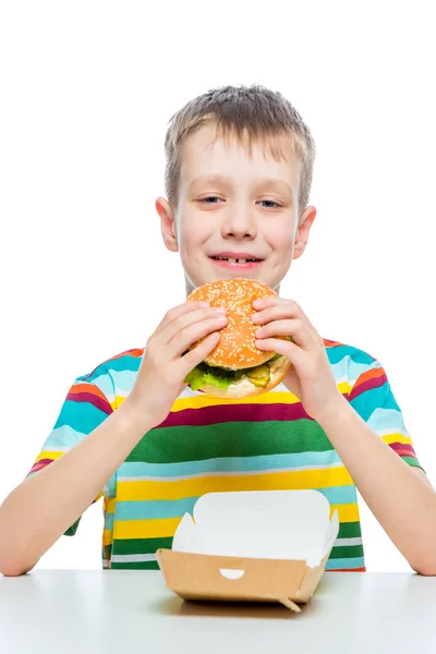 Conceito foto junk food - um menino com um hambúrguer em uma parte traseira branca — Fotografia de Stock