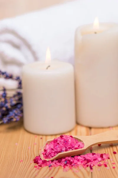 Close up sea salt in wooden spoon and burning candles soothing s Stock Picture