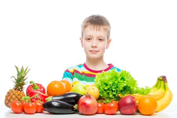 Retrato de un niño en la mesa con una pila de verduras frescas a —  Fotos de Stock