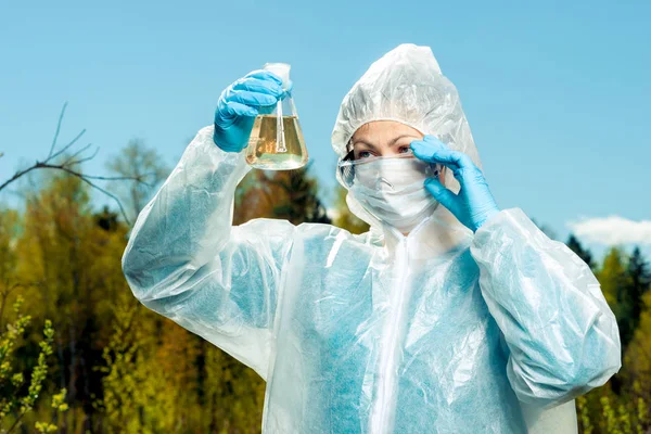 environmentalist in protective clothing and respirator examines