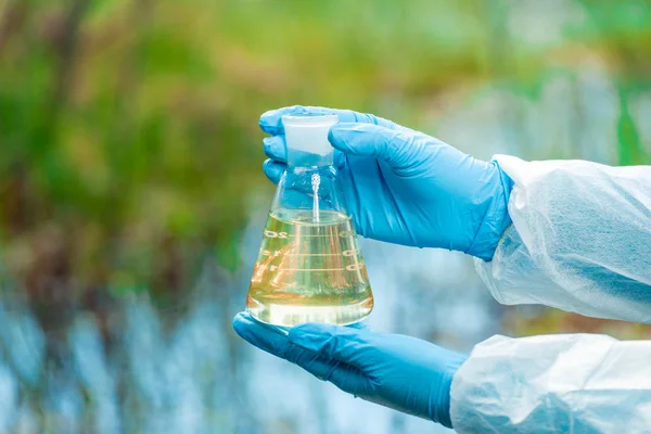 a flask with water from a lake in the hands of a environmentalis