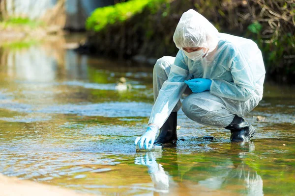 Pesquisador cientista em terno protetor leva água para análise — Fotografia de Stock