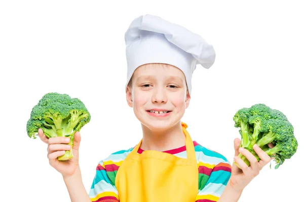 Retrato horizontal de um menino em um chapéu de cozinheiro com brócolis em um wh — Fotografia de Stock