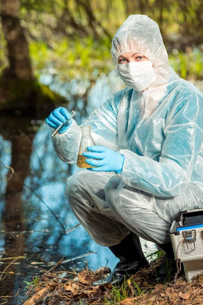 Ecologista e com tubos de ensaio e frascos analisa água em um para — Fotografia de Stock